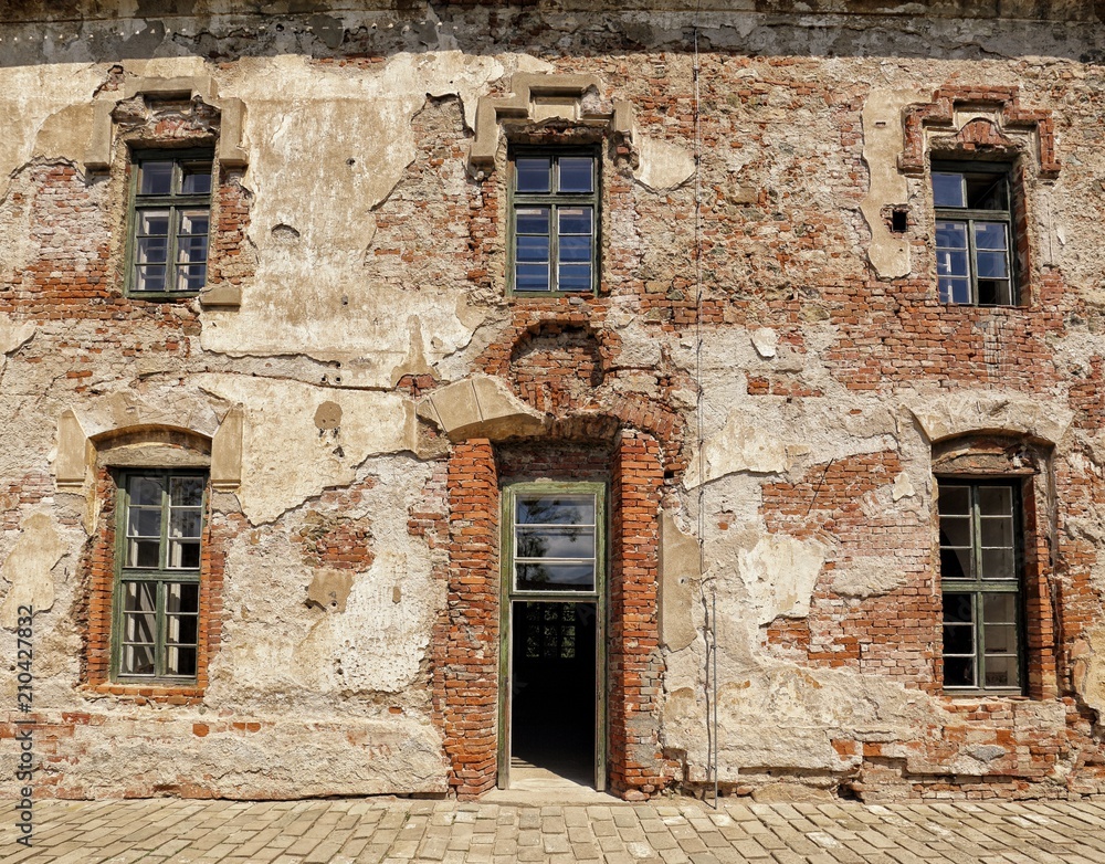 Old broken facade of the large house with wooden frame windows