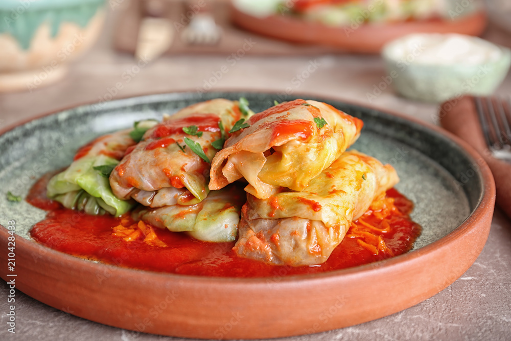 Plate with stuffed cabbage leaves in tomato sauce on table Plate with stuffed cabbage leaves in tomato sauce on table