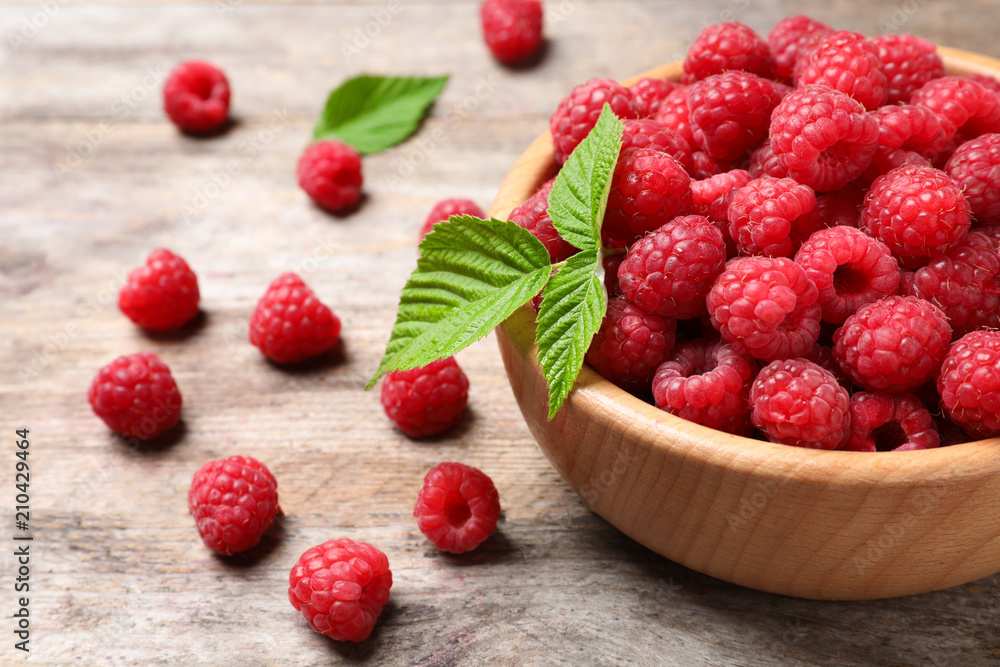 Bowl with ripe aromatic raspberries on wooden table Bowl with ripe aromatic raspberries on wooden table