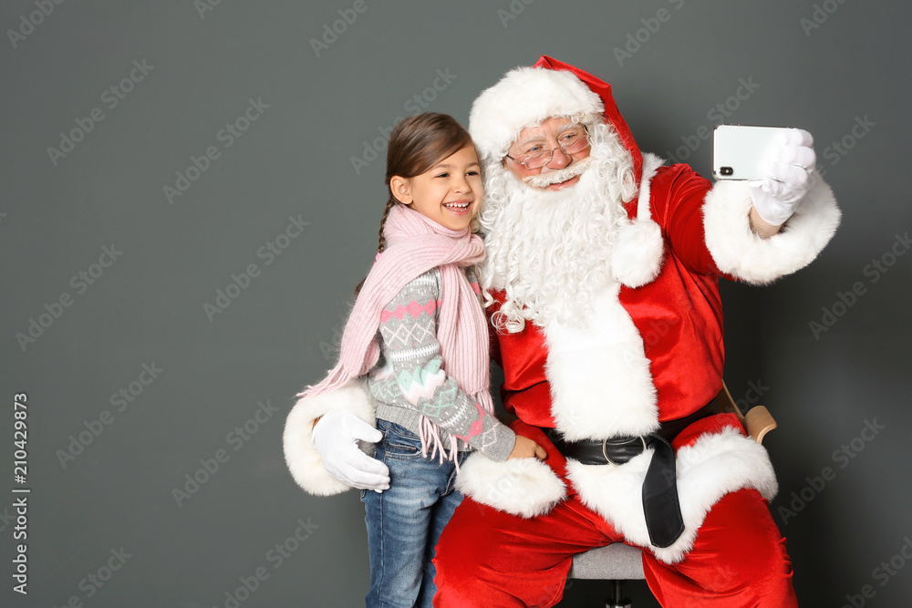 Obraz premium Authentic Santa Claus taking selfie with little girl on grey background