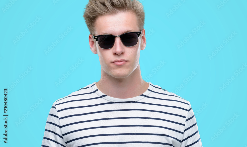 Young handsome blond man wearing sunglasess with a confident expression on smart face thinking serious Young handsome blond man wearing sunglasess with a confident expression on smart face thinking serious