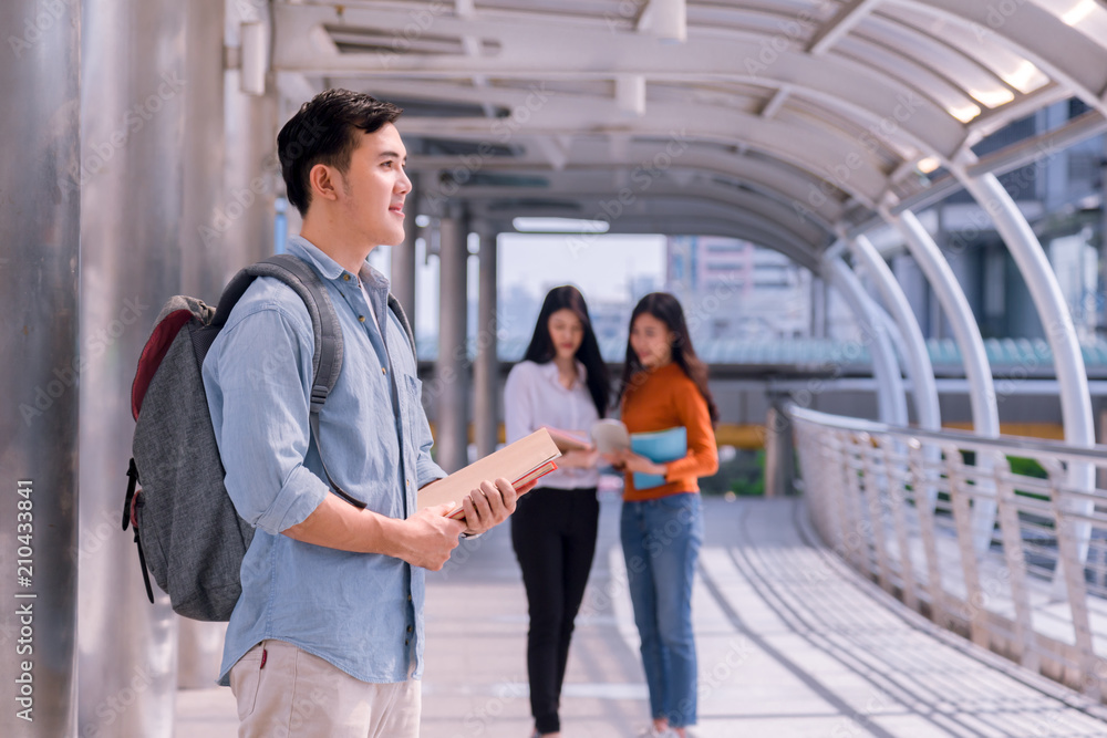 Young man college student with book in college campus. University student going to college. Young man college student with book in college campus. University student going to college.