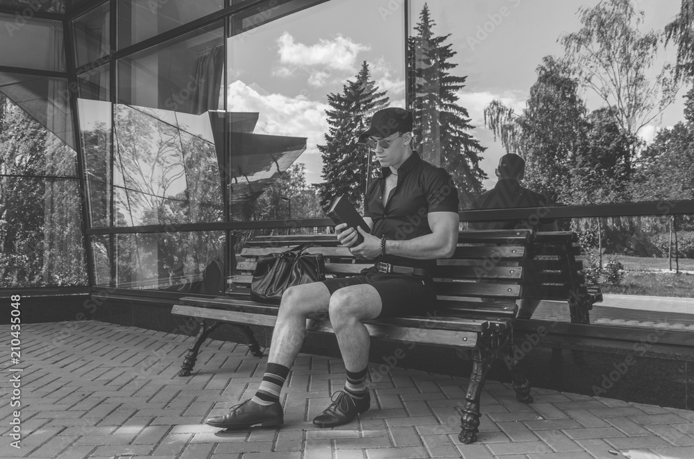 Obraz premium a student in a shirt and glasses reading a book in the city Park