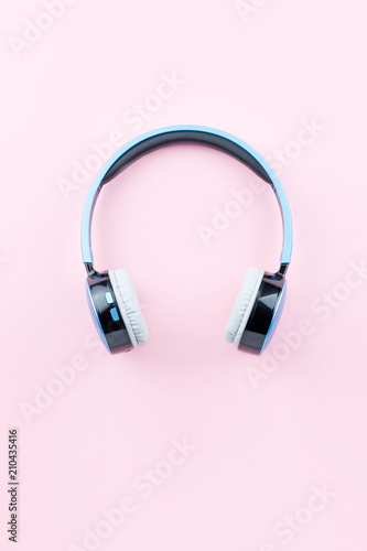 Blue wireless headphones close up on pastel pink background. Flat lay, top view