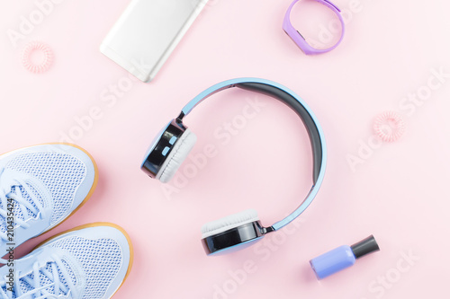 Woman sneakers, headphones, fitness tracker and smartphone on pastel pink background. Sport fashion concept. Flat lay