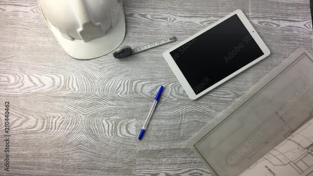 Mesa de trabajo con planos y tablet.