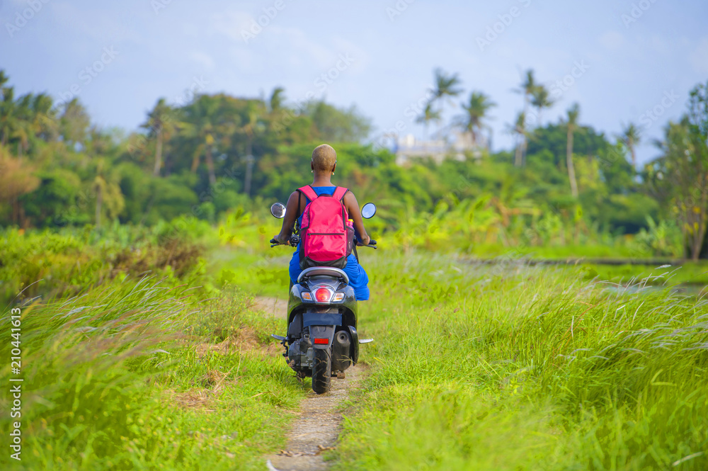 Obraz premium young attractive tourist afro American black woman riding motorbike happy in beautiful Asia countryside along green rice fields smiling free on her scooter