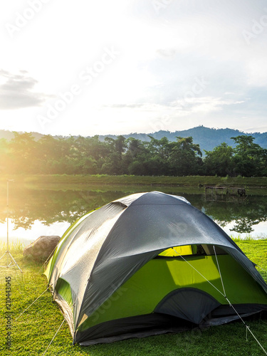Green camping tent near lagoon in the morning light