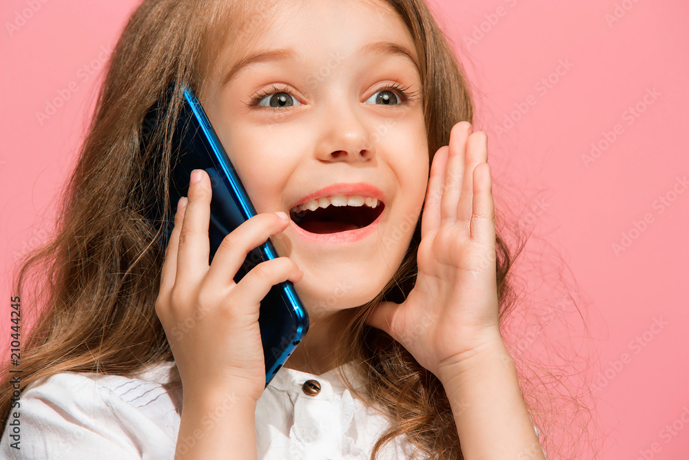 The happy teen girl standing and smiling against pink background.
