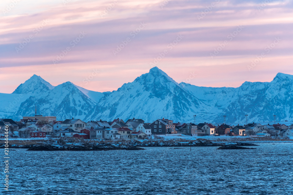 Andenes view from the nordic sea at sunset with a grey pink sky and blue mountain on the back