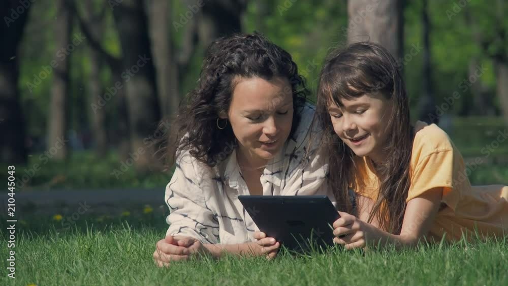 Happy family in the park. Mother with daughter with a tablet in the park. Happy family in the park. Mother with daughter with a tablet in the park.