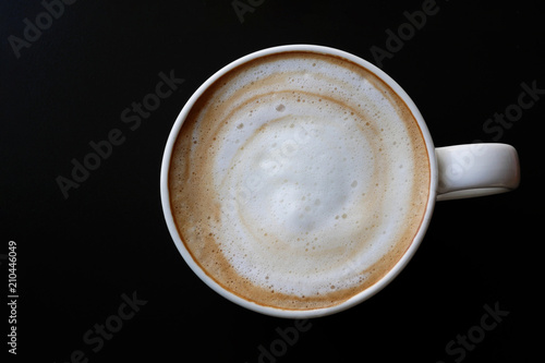 Top view of hot coffee latte cappuccino spiral foam in ceramic cup on dark background