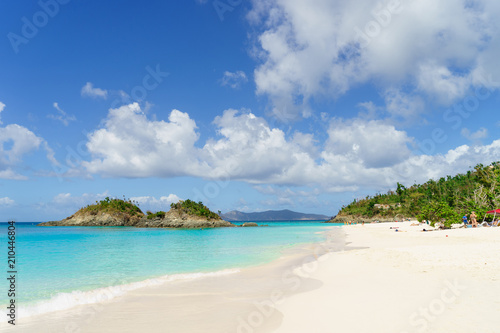 White long beach with crystal blue water and small green hill on background