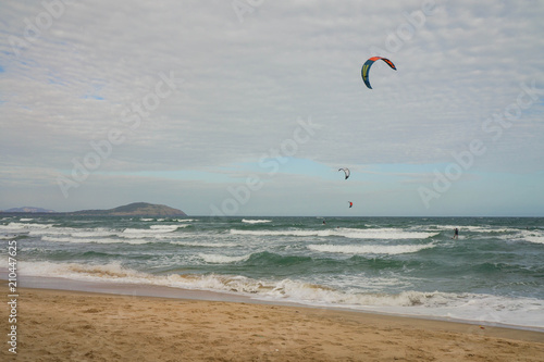 Picturesque view of the coast with kite surfers on waves.