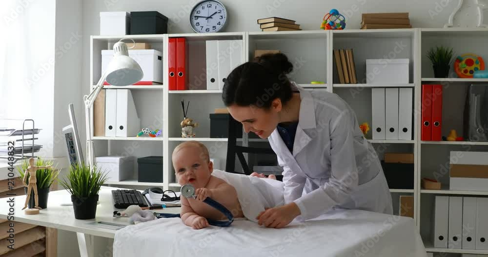 child playing with stethoscope while doctor standing next to him in office . child playing with stethoscope while doctor standing next to him in office .
