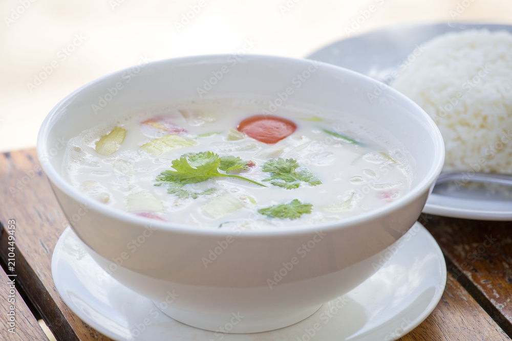 Tom kha kai on wooden table. Tom Kha Gai is Thai coconut soup is a spicy and sour hot soup with coconut milk in Thai and Lao cuisine Tom kha kai on wooden table. Tom Kha Gai is Thai coconut soup is a spicy and sour hot soup with coconut milk in Thai and Lao cuisine