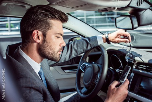 side view of businessman using smartphone while driving car