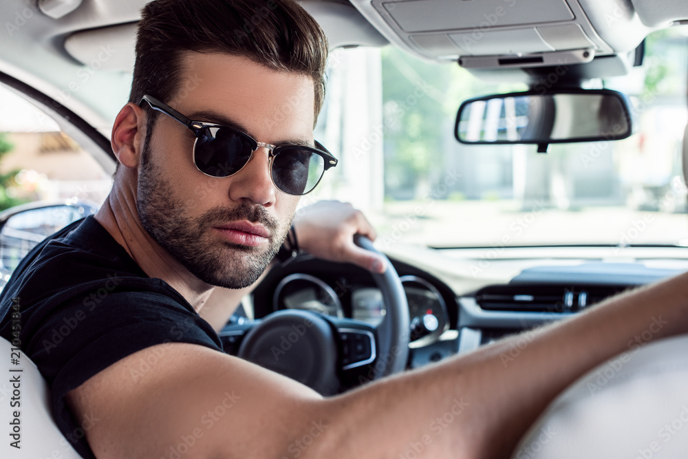 portrait of serious stylish man in sunglasses looking back while driving  car Stock Photo | Adobe Stock