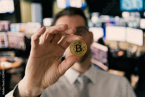 Professional currency trader in market exchange office holding Bitcoin in hand