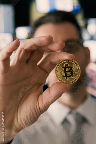 Professional trader holding Bitcoin in hand in exchange office, portrait.