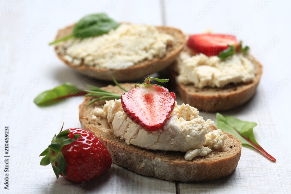 Slices of bread with white cheese and strawberries on top Slices of bread with white cheese and strawberries on top