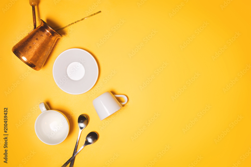 Turkish cezve, espresso cups and plate concept of coffee making and drinking. Yellow background, flatlay, copyspace