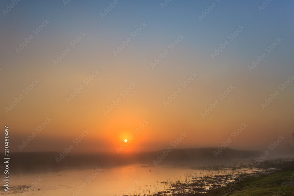 Foggy landscape with sunrise over the river