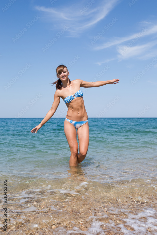 Young woman in bikini comes out from seawater Young woman in bikini comes out from seawater