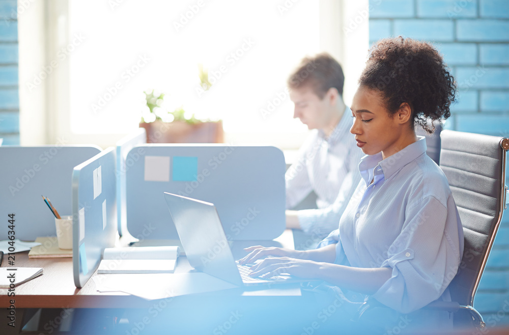 Young woman concentrating on searching information in the net while sitting by individual workplace Young woman concentrating on searching information in the net while sitting by individual workplace