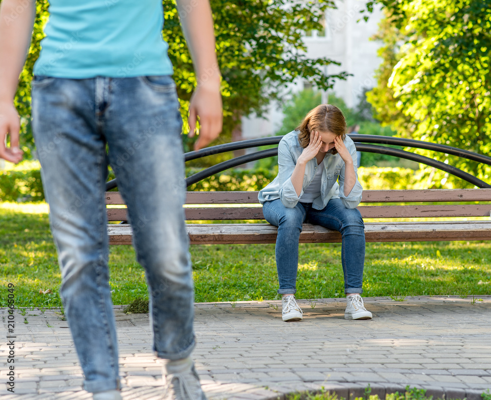 The guy leaves the young girl. This park is in nature. A girl is sad and crying is sitting on a bench. The concept of problem in the family and breaking the relationship. The guy leaves the young girl. This park is in nature. A girl is sad and crying is sitting on a bench. The concept of problem in the family and breaking the relationship.