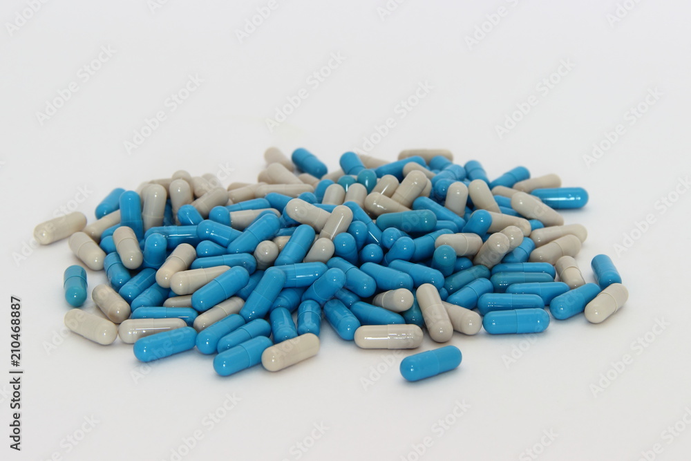 A mixture of blue and gray pills - a lot of capsules on a white background: vitamin, antibiotic, sleeplessness, insomnia, flu, acute respiratory infections, autumn