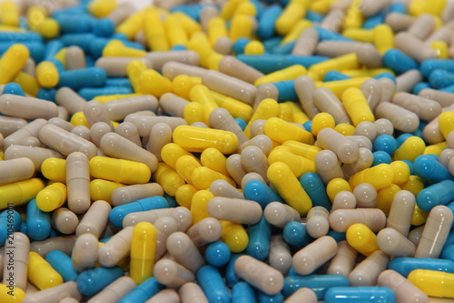 Scattered multi-colored pills – blue, gray and yellow capsule, close-up photo