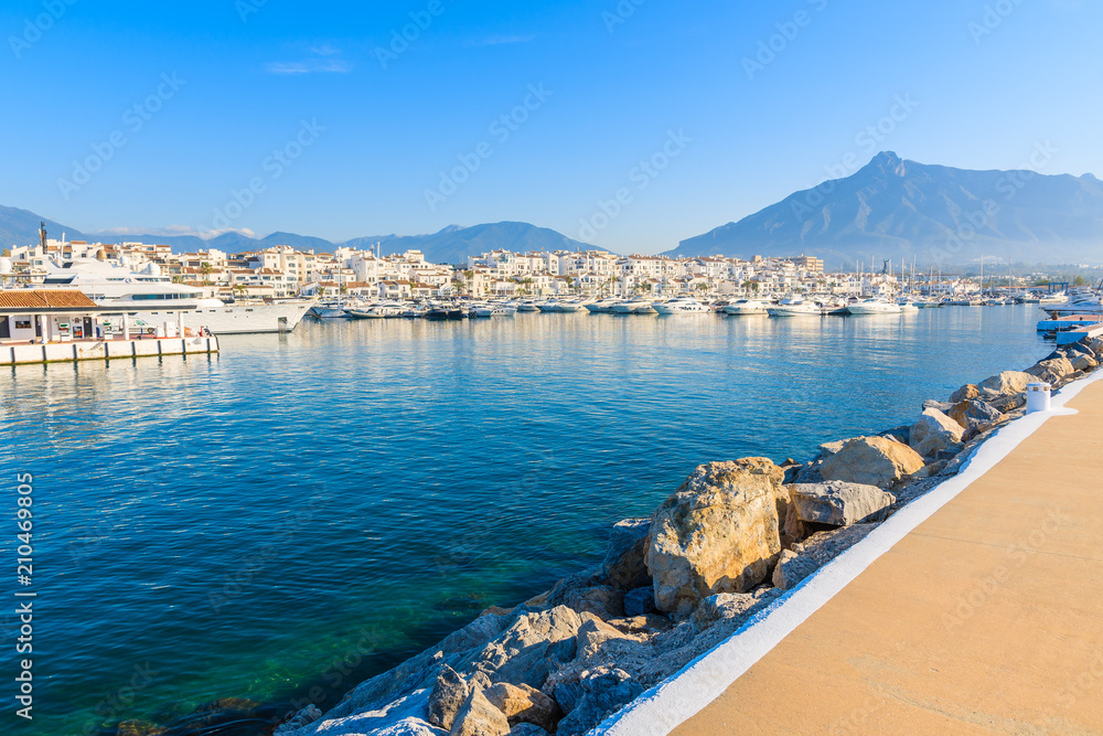 View of Puerto Banus marina with boats and white houses in Marbella town at sunrise, Costa del Sol, Spain