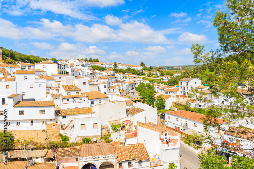 White houses of Andalusian village on green hills and sunny sky with clouds, Sentinel de las Bodegas, Spain