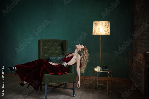 Beautiful blonde in black velvet dress on aristocratic apartment background. photo