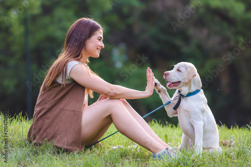 Photography Beautiful young girl playing with a puppy labrador in the park