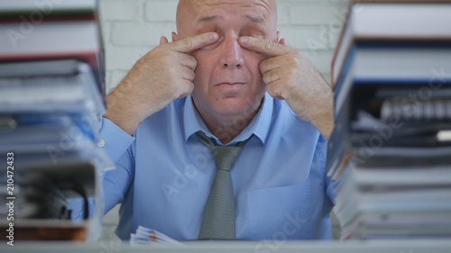 Businessman In Office Room Rubbing His Tired Eyes With Hands photo