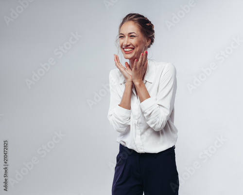 beautiful businesswoman in white blouse and black pants fun laughing and rejoicing at victory against white background in studio