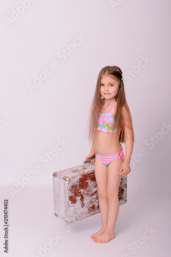 Cute little  girl are standing with old suitcase.