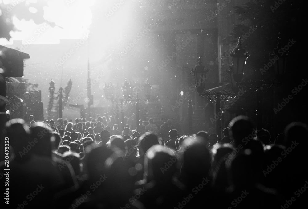 Black and white silhouette of people crowd walking down the pedestrian street under the sunshine