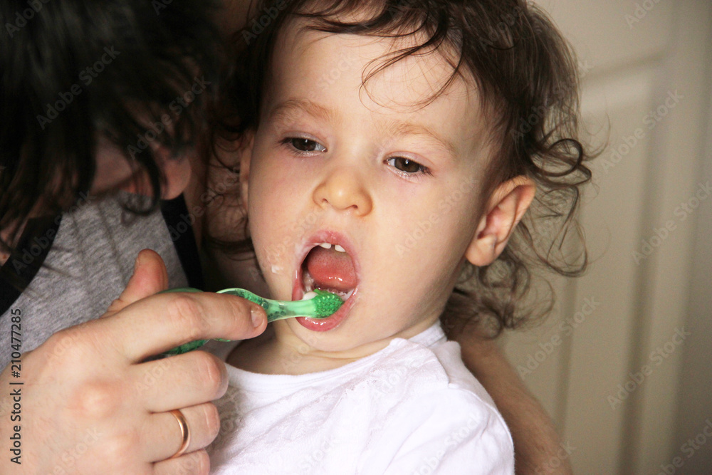 A caring good father gently carefully brushes his little daughter's teeth in the bathroom A caring good father gently carefully brushes his little daughter's teeth in the bathroom