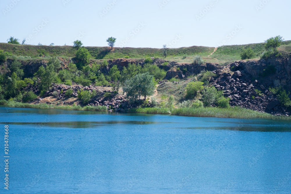 beautiful landscape of a cliff near a reservoir, depth, cliff, grass, stones, sand, blue sky