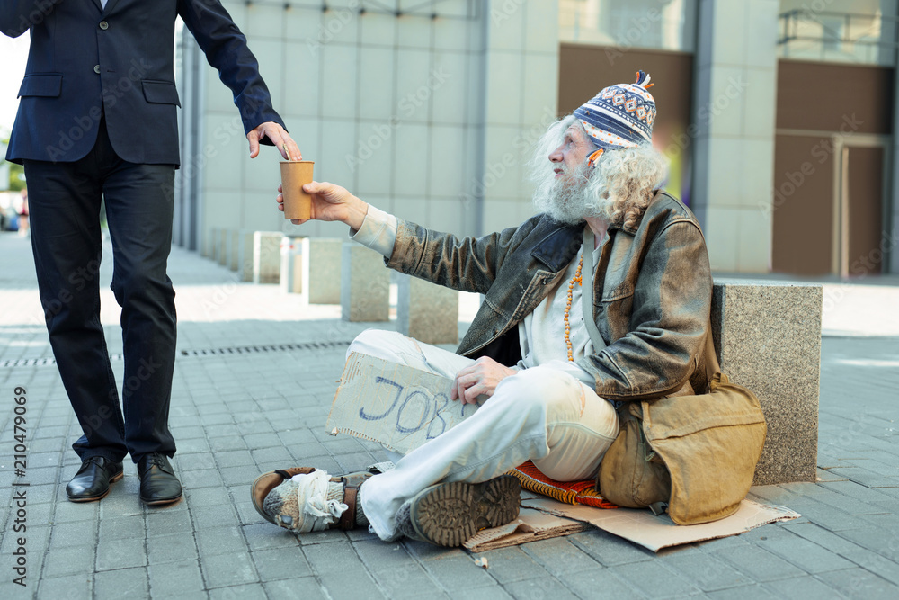 Street person. Poor helpless street person feeling lost while sitting on  the street begging for help and some money Stock Photo | Adobe Stock