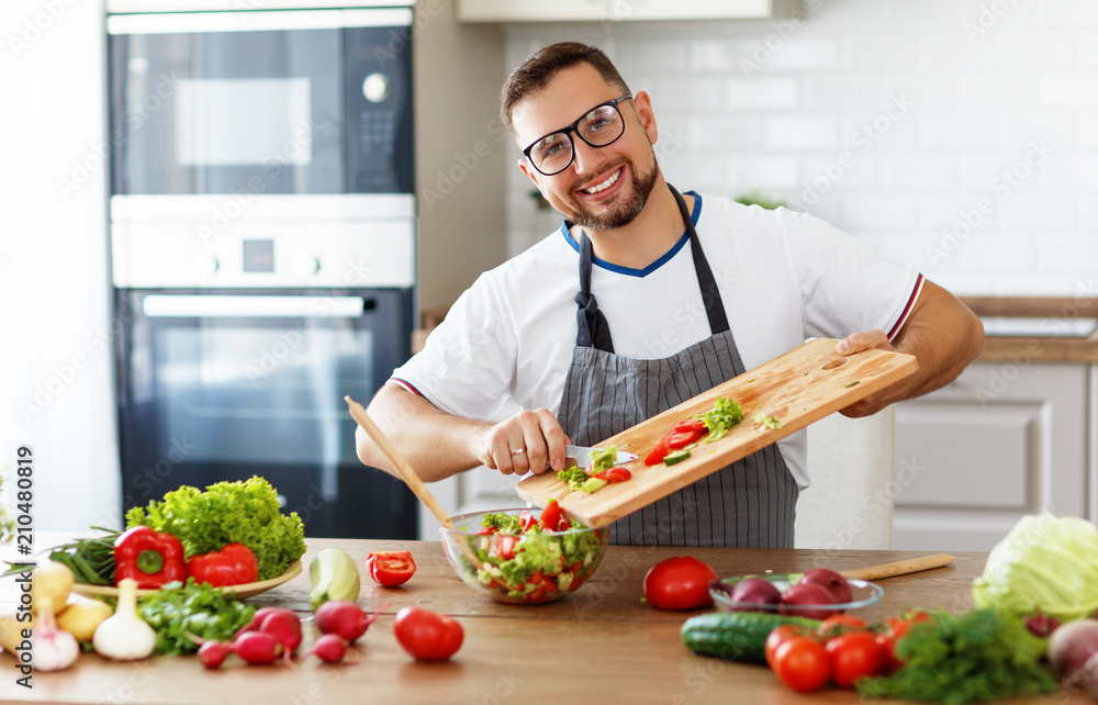happy man preparing vegetable salad in kitchen happy man preparing vegetable salad in kitchen