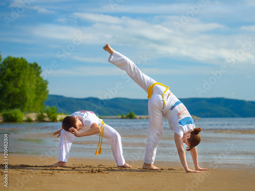 A woman and a boy to train capoeira on the beach