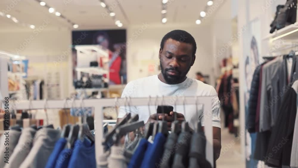 Attractive african american young man using phone texting message walk at store chooses clothes internet happy black telephone portrait cute mobile holding slow motion handsome portrait Attractive african american young man using phone texting message walk at store chooses clothes internet happy black telephone portrait cute mobile holding slow motion handsome portrait