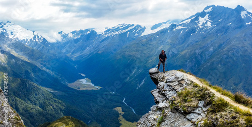 traveler standing at the edge of a cliff with a valley in the distance © Ooriya