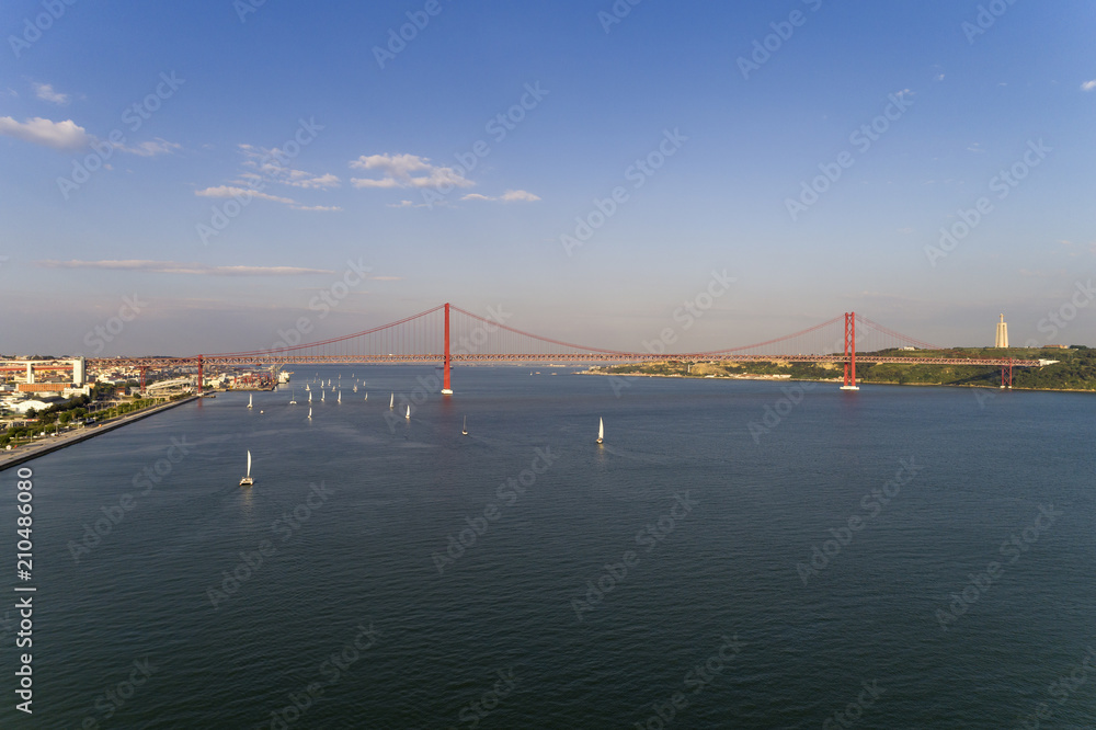 Aerial view of the city of Lisbon with sailboats on the Tagus River and the 25 of April Bridge on the background; Concept for travel in Portugal and visit Lisbon