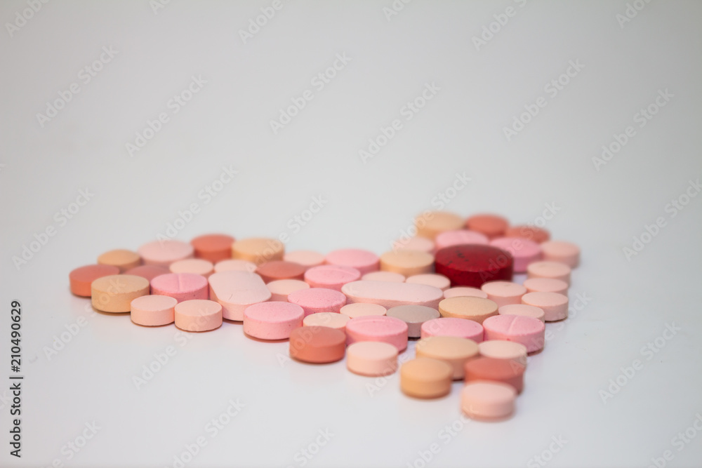 Multiple white and pink and red pills on a white background with several of them out of focus. Medications in the form of tablets. Multiple white and pink and red pills on a white background with several of them out of focus. Medications in the form of tablets.