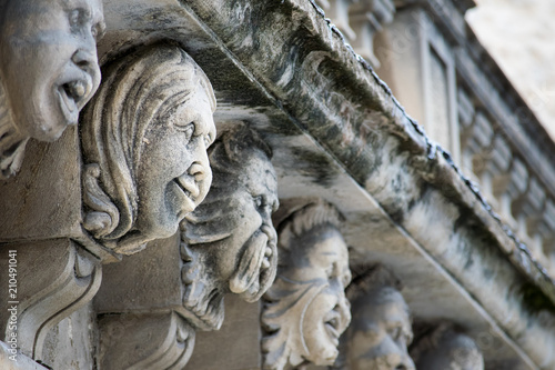 Closeup view of mascarons with funny faces under the balcony of a baroque palace in the province of Syracuse, Sicily photo